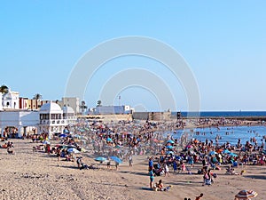 People sunbathing at sunset on the beach of La Caleta in the bay of Cadiz, Andalusia. Spain.