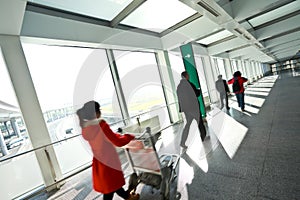 People in sunny windows modern airport station aisle