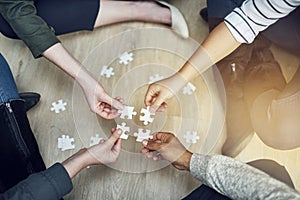 People, support and hands with puzzle on floor for problem solving, strategy and synergy in training. Team, diversity