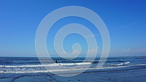 People surfing on sea waves under blue sky. Katase Nishihama beach is one of Japan`s most popular beaches