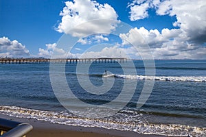 People surfing in vast blue ocean water with waves rolling into the beach at Surfers Point at Seaside Park