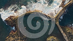 People swim in natural pool on the ocean, Tenerife island, Canary. Aerial view natural pool in Los Gigantes, Tenerife