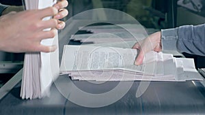 People take paper from typographical conveyor, close up.