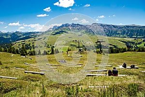 Relaxing on wooden benchs in the wideness of Alpine meadows of Seiser Alm, Alpe de Siusi, South Tyrol,  Italy photo