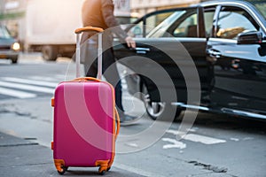 People taking taxi from an airport and loading carry-on luggage bag to the car. photo