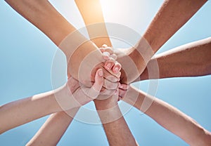 People, teamwork and hands together below for unity, collaboration or synergy on a blue sky background. Closeup or low