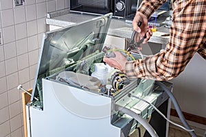 People in technician jobs. Appliance repair technician or handyman works on broken dishwasher in a kittchen. Laborer is changing