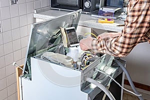 People in technician jobs. Appliance repair technician or handyman works on broken dishwasher in a kittchen. Laborer is changing