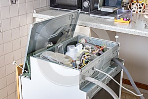 People in technician jobs. A broken built-in dishwasher in a white kitchen was removed from the kitchenette then turned upside