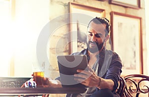 Man with tablet pc drinking beer at bar or pub