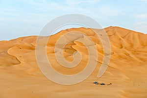 People with tents and cars among dunes in Rub al-Khali desert (Oman)