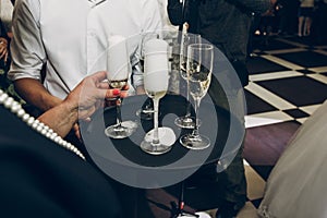 people toasting with champagne glasses at wedding reception, waiter serving on tray champagne drinks, celebration catering