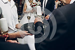 people toasting with champagne glasses at wedding reception, waiter serving on tray champagne drinks, celebration catering