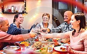 People toasting red wine and having fun at winter holidays reunion - Dinner celebration concept with happy adult friends