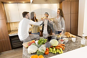 People toasting with white wine in the kitchen
