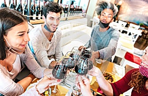 People toasting wine at restaurant wearing face masks - New normal lifestyle concept with happy friends having fun together