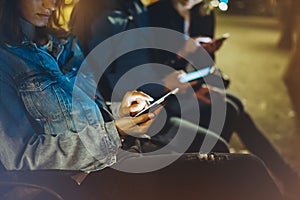 People together pointing finger on screen smartphone on background bokeh light in night atmospheric city, group adult hipsters fri