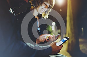 People together pointing finger on screen smartphone on background bokeh light in night atmospheric city, group adult hipsters