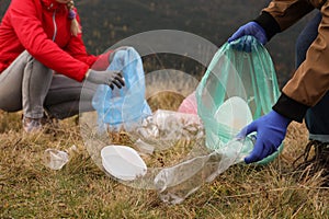 People with trash bags collecting garbage in nature, closeup