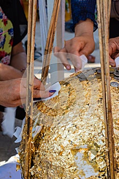 People try to stick a gold leave on buried stone when thai traditional Fung Luuk Nimit