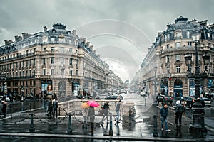 People under colored umbrellas run in the rain on the streets of Paris, France