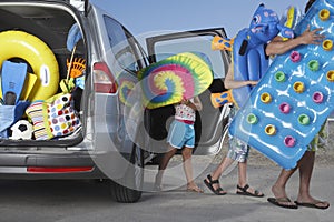 People Unloading Beach Accessories From Car