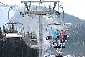 People using chairlift at mountain ski resort. Winter