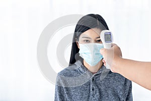 People using infrared Thermometer For measuring the temperature of women Wearing a surgical mask