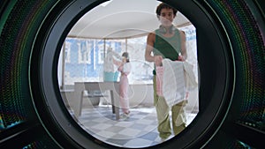 People using laundromat room in city. Closeup young hispanic man loading clothes