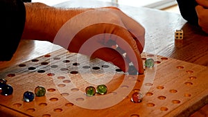 People using olored marbles and dice to play a family game on a homemade board.