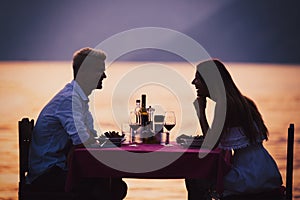 People, vacation, love and romance concept. Young couple enjoying a romantic dinner on beach. photo