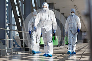 People in virus protective suits and mask disinfecting buildings