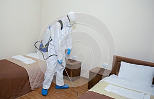 People in virus protective suits and mask disinfecting buildings of coronavirus with the sprayer