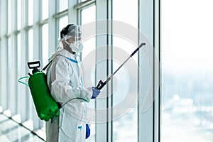 People in virus protective suits and mask disinfecting buildings of coronavirus with the sprayer