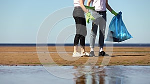 People in volunteer t-shirts pick up plastic trash from beach sand. Spbi eco community activists