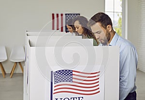 People voting standing in a row at polling station at vote center with usa flags.