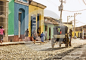 People walk along street as horse-drawn taxi passes, in Trinidad, Cuba.