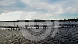 People walk and kids run on a pier at Lake Siljan on a cloudy summer evening