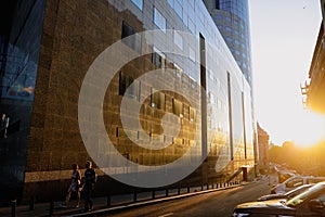 People walk near a tall glass office building at twilight in the old center of Bucharest