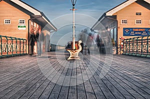 People walk past the bench at penarth peir