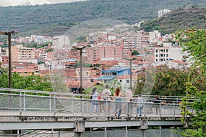 people walk on a pedestrian bridge leading to a shopping center, on a sunny summer day