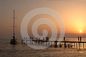 People walk on pier on sunset