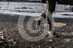 People walk on a slippery road made of melted ice. View of the legs of a man walking on an icy pavement. Winter road in the city.