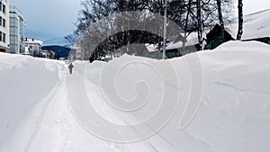 People walk on town road after massive blizard. Cleared road after a snow storm in the city.