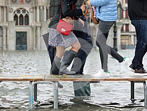 people walk on a walkway in Piazza San Marco because of the high