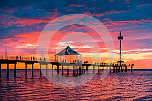 People walking along Brighton jetty at sunset