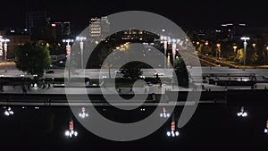 People walking along city`s night promenade at night. Stock footage. Top view of busy bridge in center of modern city at