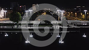 People walking along city`s night promenade at night. Stock footage. Top view of busy bridge in center of modern city at