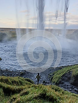 People walking behind waterfall