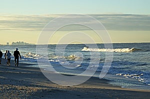 People walking bonita beach with surfer at sunrise photo